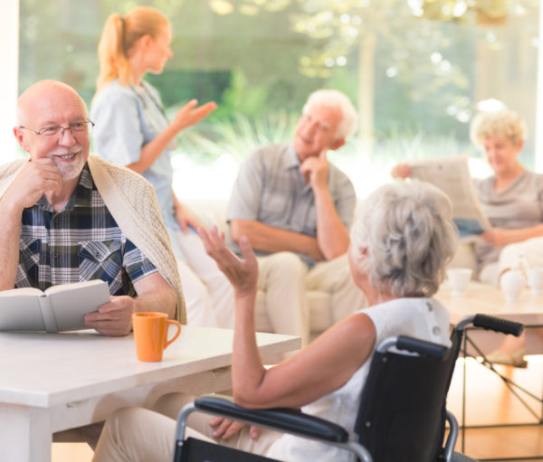 a group of seniors gathered a common area of an assisted living community