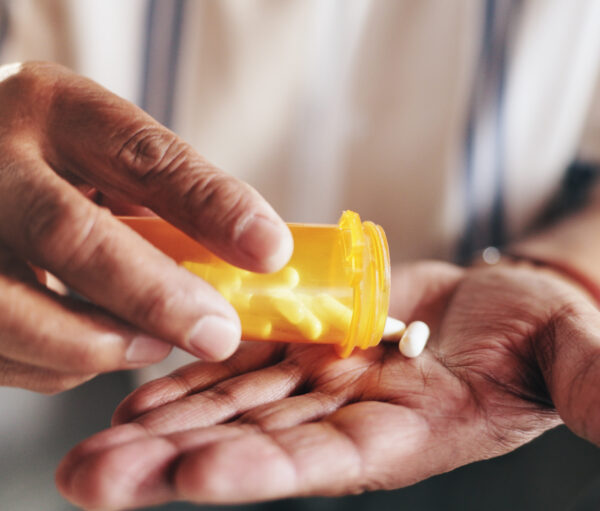 Hands, pills and bottle in closeup for person with drugs, routine and schedule for health in home. Elderly patient, container and pharma product for supplements, wellness or benefits in retirement